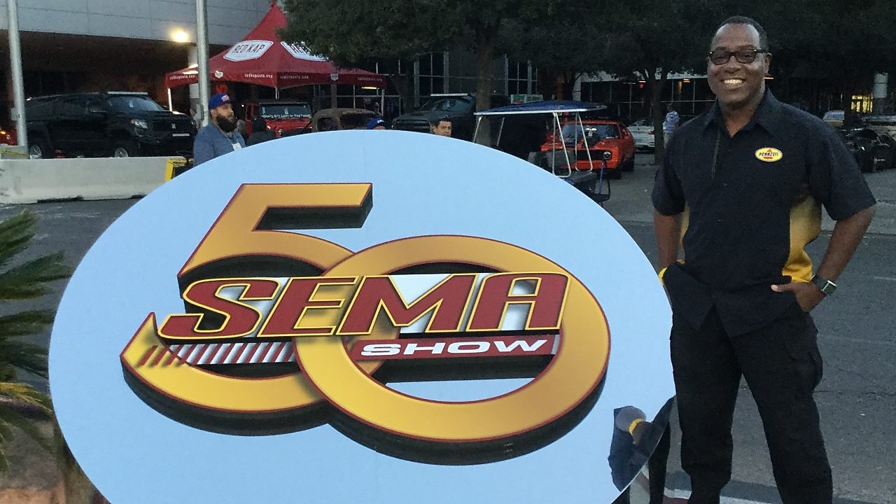 Michael beside large SEMA sign