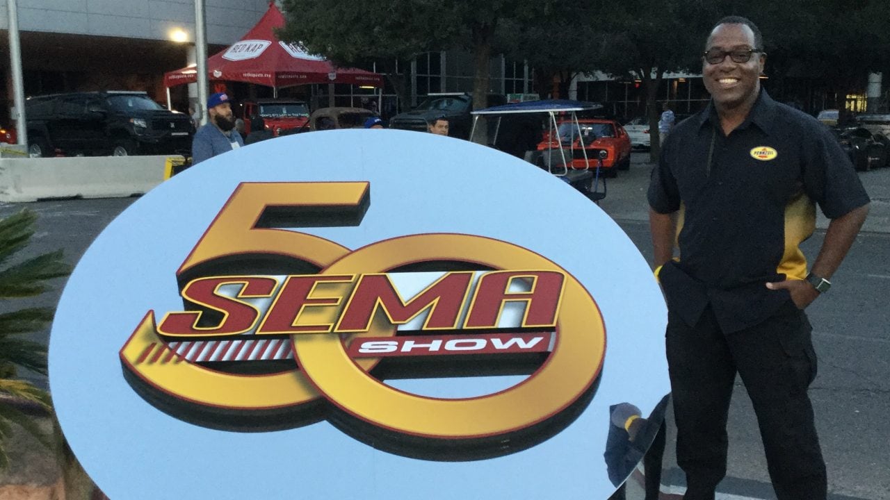 Michael beside large SEMA sign