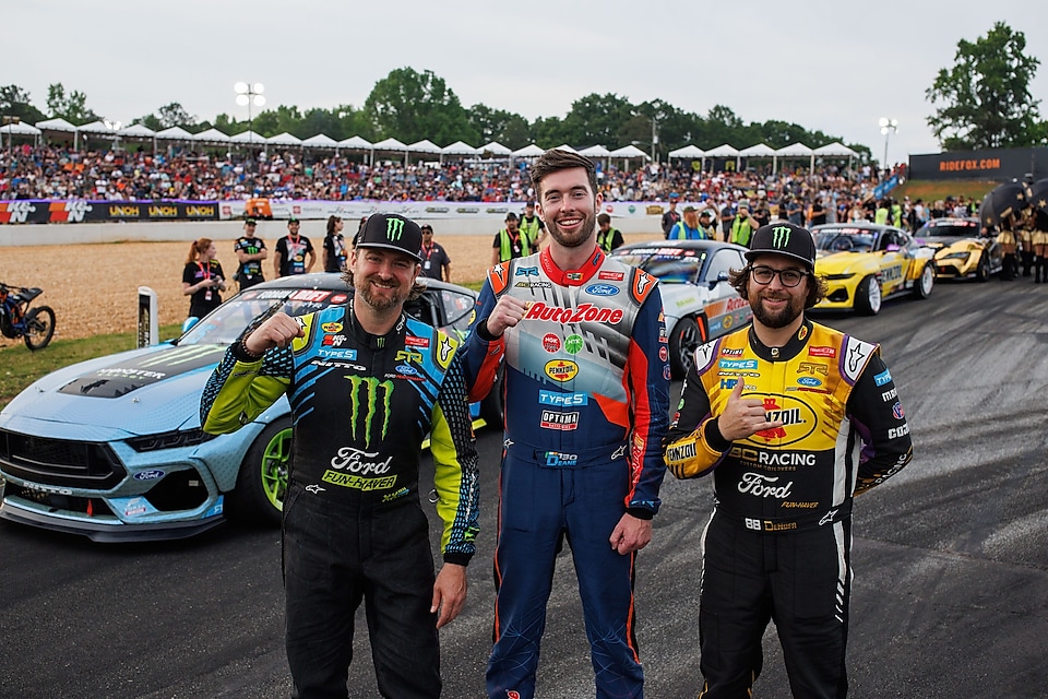 three men in front of racecar