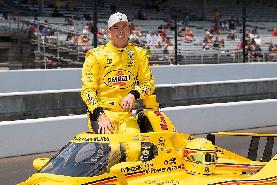 Man in yellow racesuit sitting on racecar