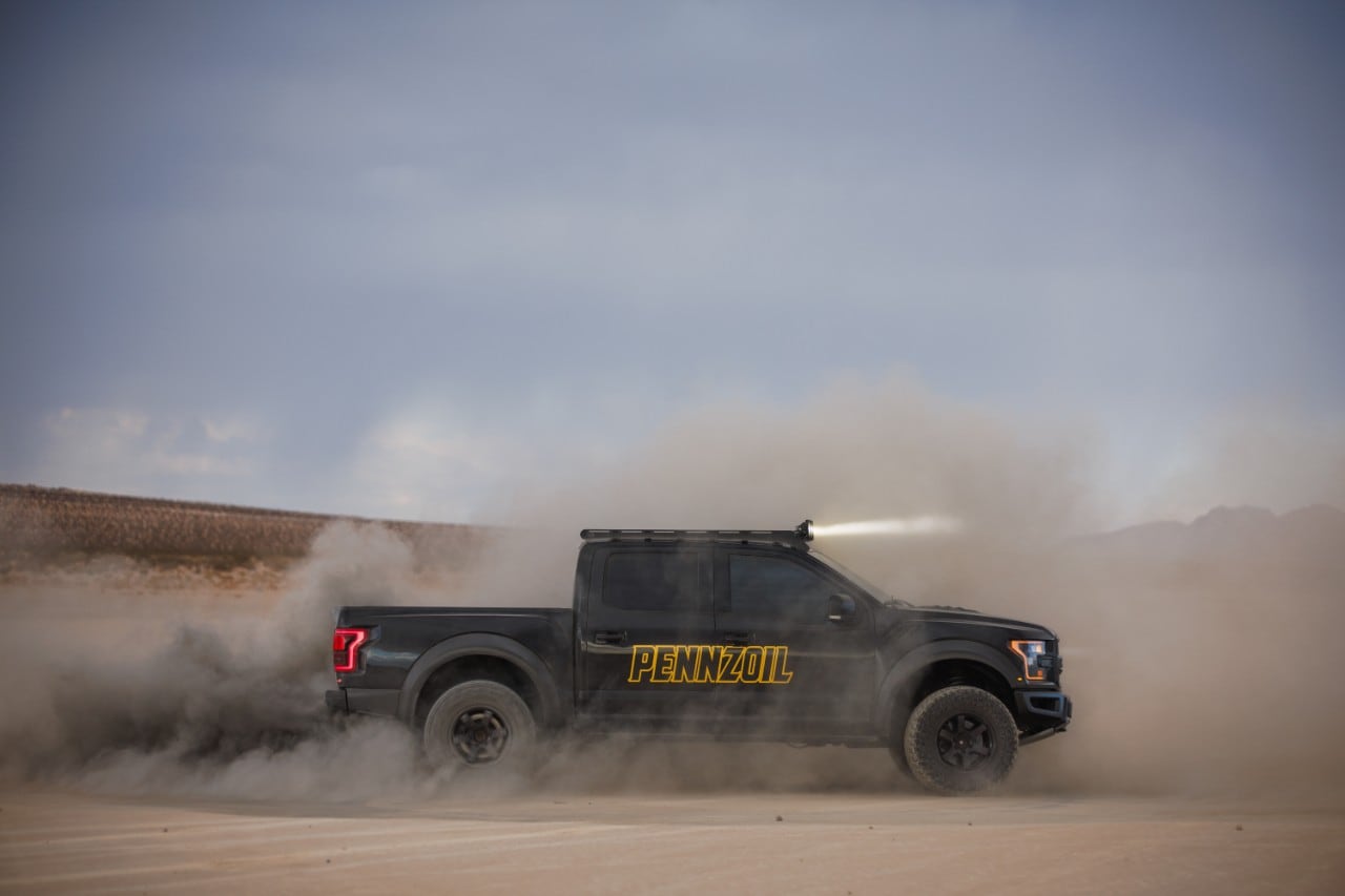 A black truck driving on a dirt road