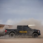 A black truck driving on a dirt road