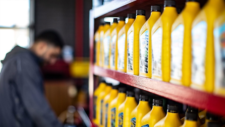 auto shop employee comparing different Pennzoil motor oils – click to learn more about how Shell Lubricants is helping combat the world’s shortage of qualified automotive technicians.