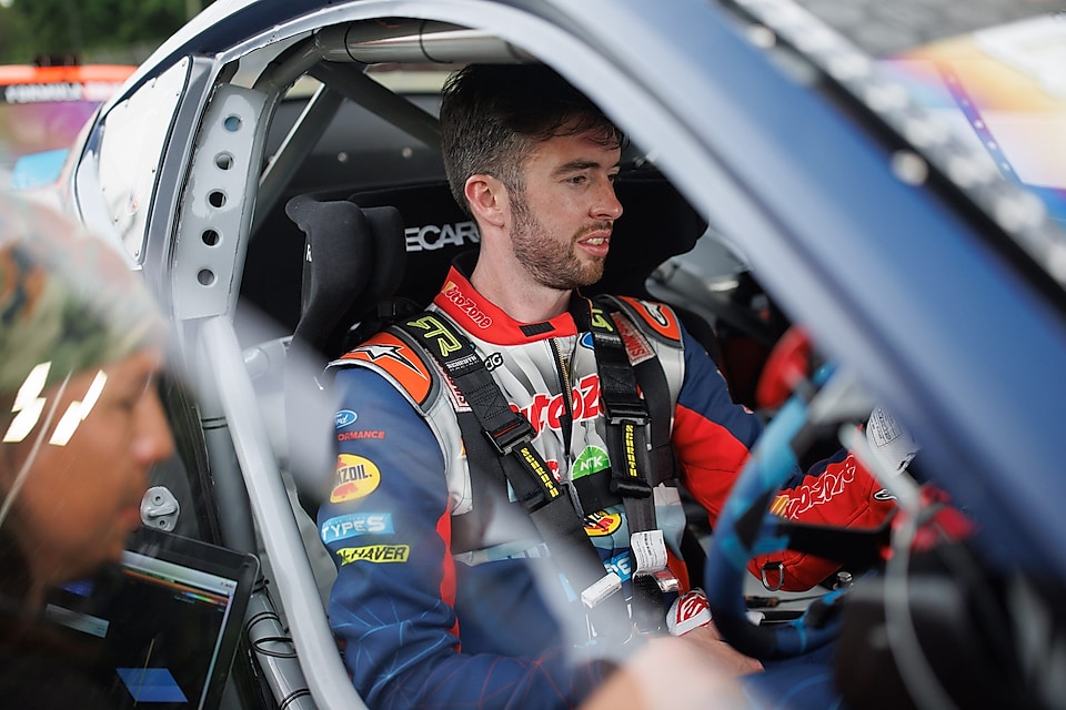 Man in racing suit sitting in car