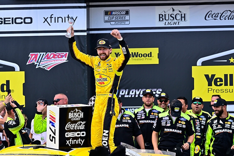 Man in yellow racesuit with arms in the air