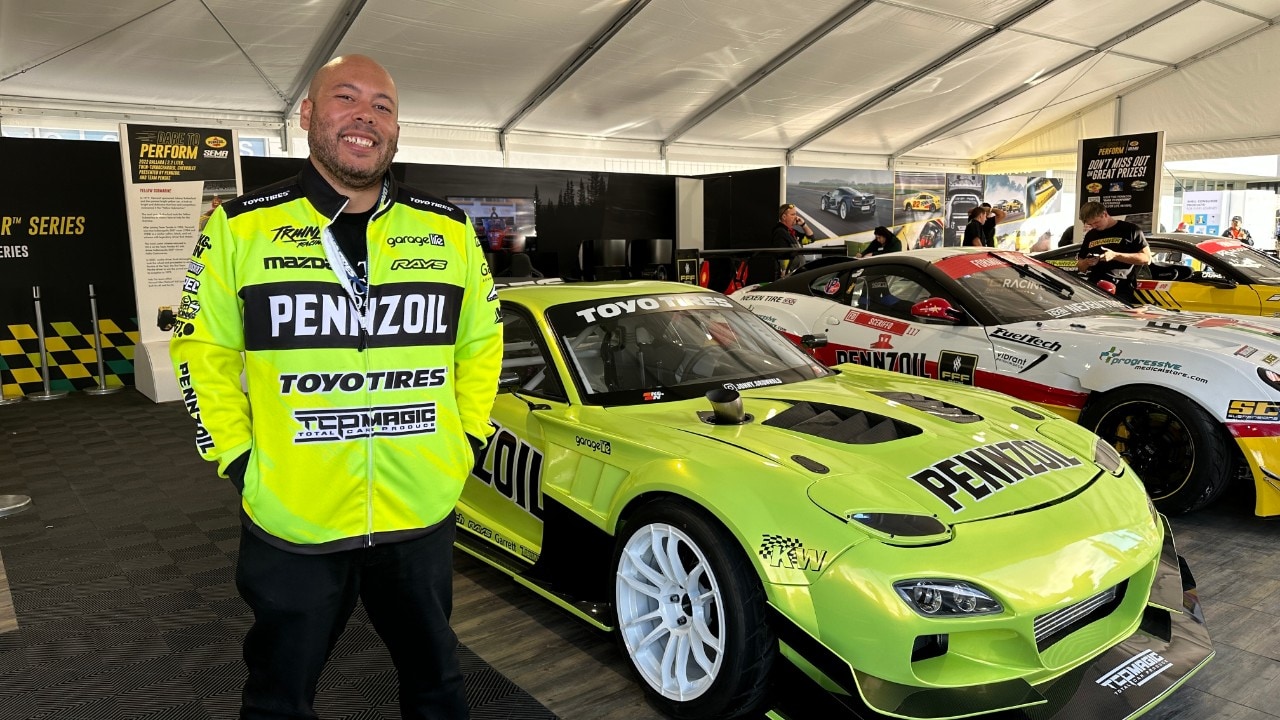 A person standing in front of a green car