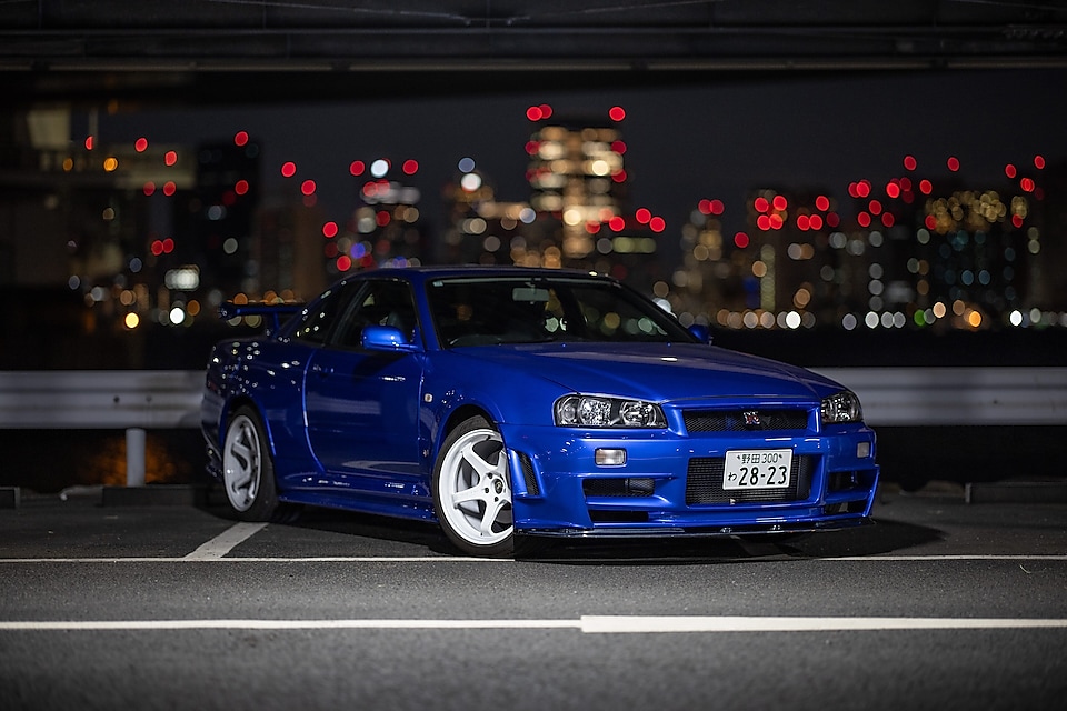 La voiture R34 GT-R restaurée de Larry Chen sous les lumières de la ville.