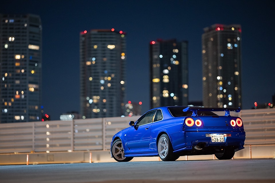 La voiture R34 GT-R restaurée de Larry Chen sous les lumières de la ville.