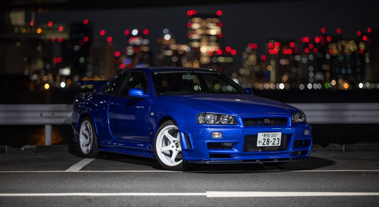 La voiture R34 GT-R restaurée de Larry Chen sous les lumières de la ville.