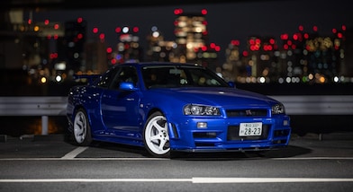 La voiture R34 GT-R restaurée de Larry Chen sous les lumières de la ville.