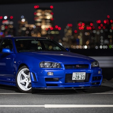 La voiture R34 GT-R restaurée de Larry Chen sous les lumières de la ville.