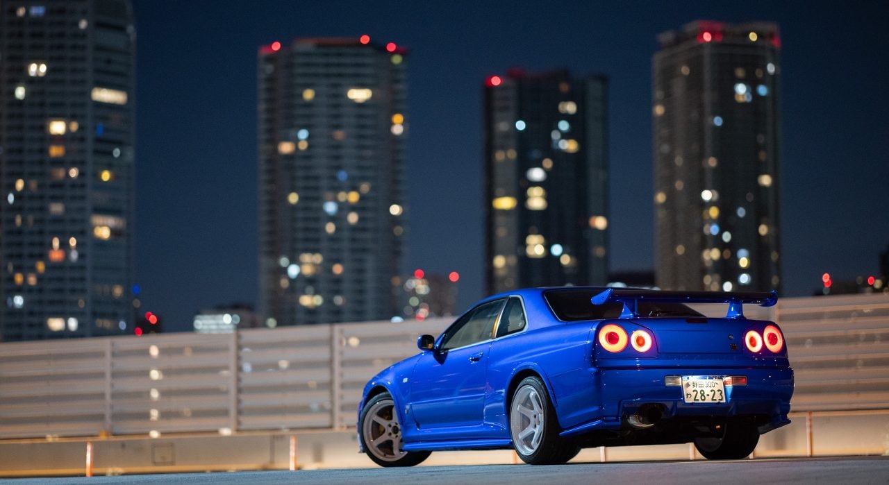 La voiture R34 GT-R restaurée de Larry Chen sous les lumières de la ville.