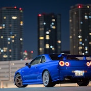 La voiture R34 GT-R restaurée de Larry Chen sous les lumières de la ville.