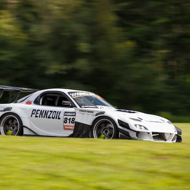 Une voiture de course blanche sur un champ d’herbes